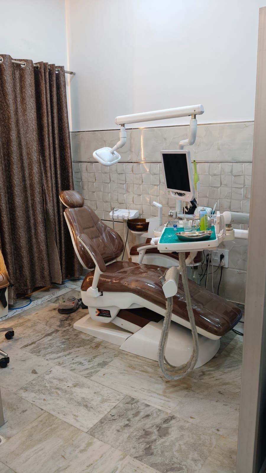 Modern dental operatory with chair, overhead light and monitor at Wisdom Dental & Maxillofacial Centre